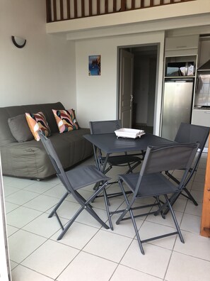 Un espace de vie compact comprenant un canapé, une table à manger avec des chaises, un réfrigérateur et une affiche accrochée au mur.
