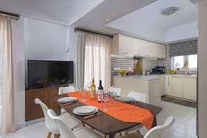A modern kitchen with a dining area, a TV, and a kitchen island.