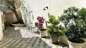 A paved patio area with a white wall, potted plants, a table, and chairs. - Studio 2 minutes from the NANCY THERMAL complex (Nancy)
