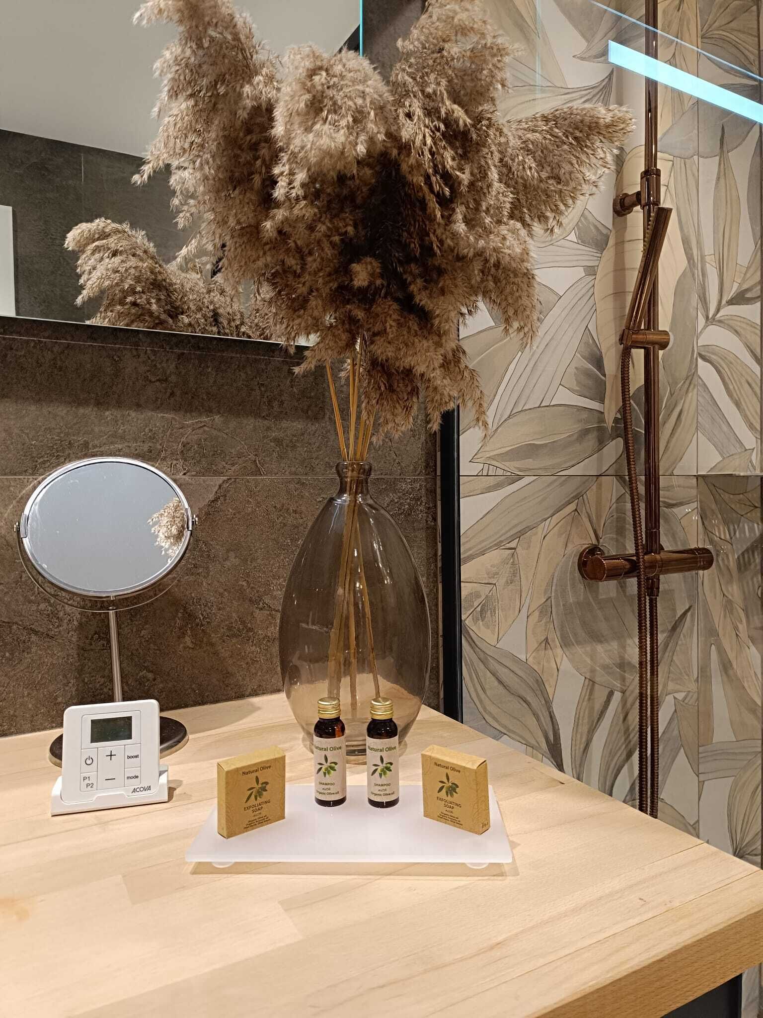 A bathroom vanity with a mirror, a scale, and three bottles of natural olive shampoo and soap.