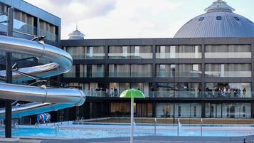 Ein modernes Gebäude mit Poolbereich, inklusive Wasserrutsche und Glasbrüstung.