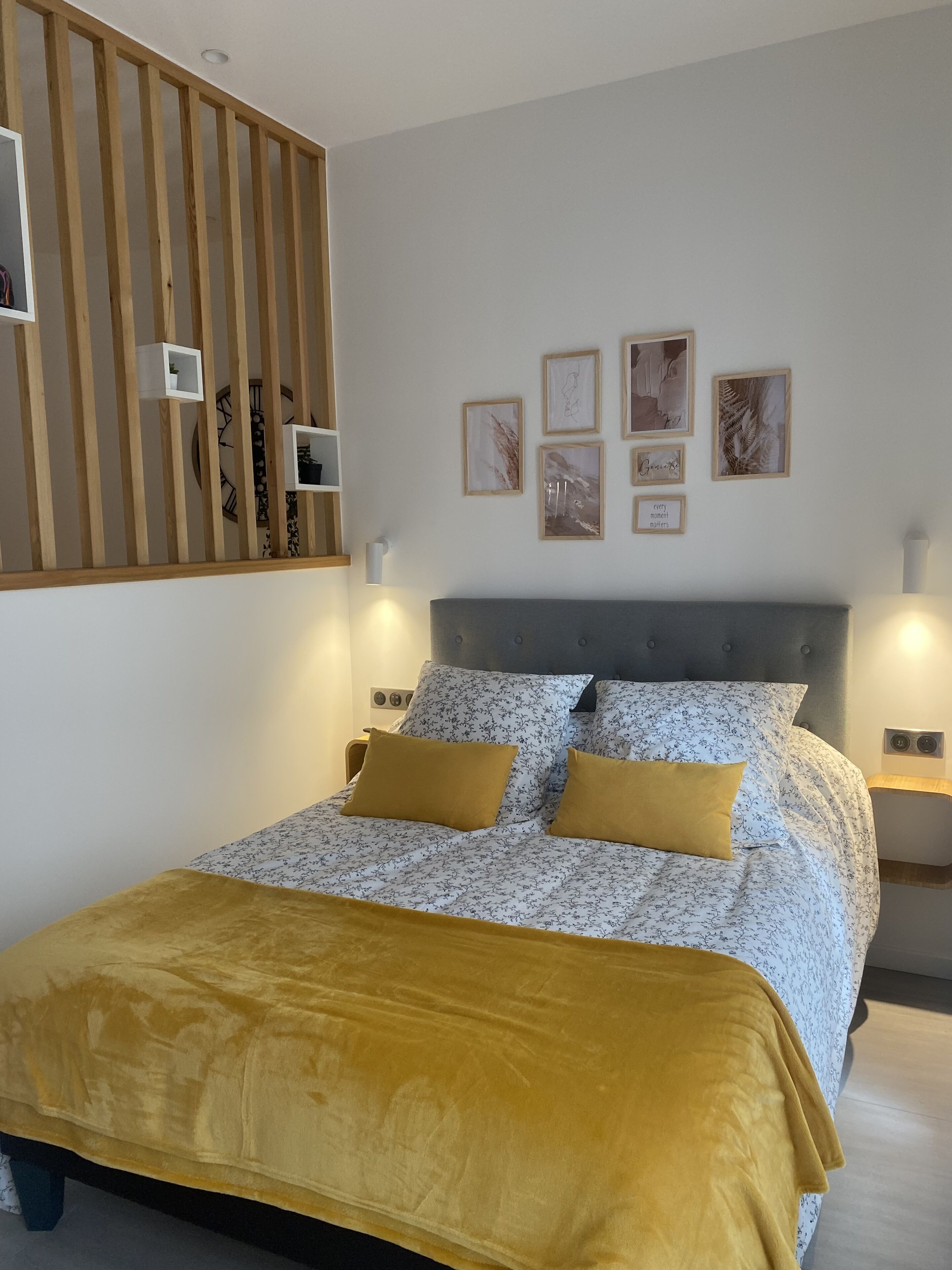 Une chambre à coucher avec un lit, un mur recouvert de lambris en bois et des tableaux encadrés accrochés au mur.