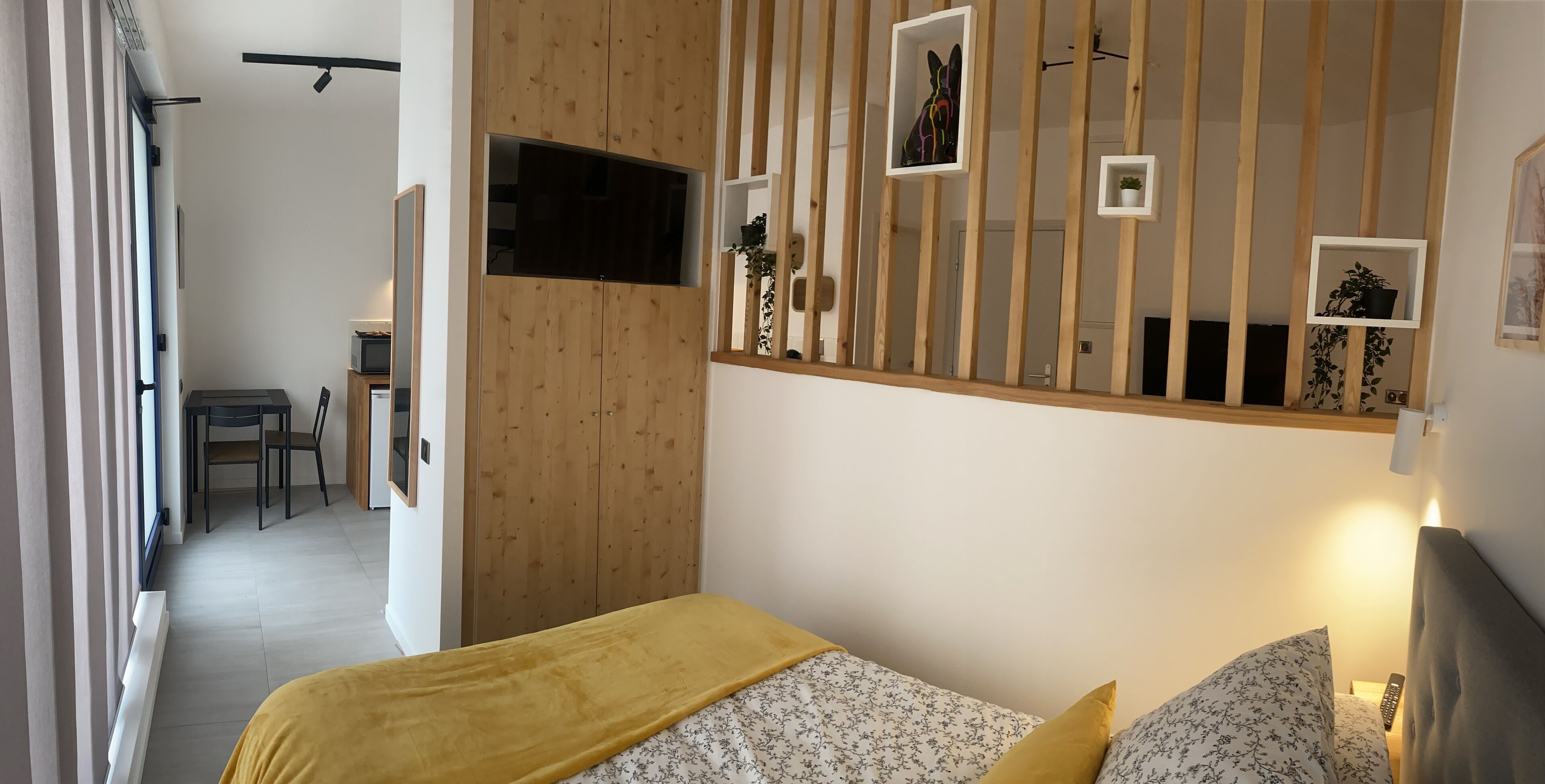 Quarto moderno com cama, televisão e guarda-roupa de madeira.
