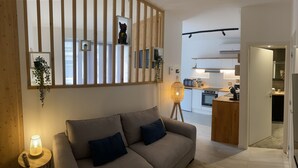 A modern living room with a sofa, a lamp, and a wooden partition with shelves. - Studio 2 minutes from the NANCY THERMAL complex (Nancy)