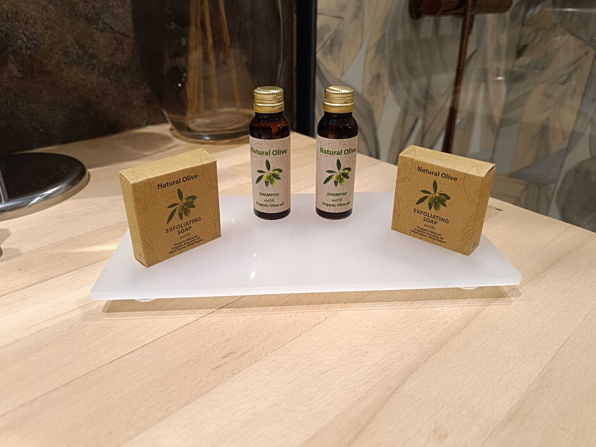 Three boxes and two bottles of Natural Olive shampoo and soap on a white surface.