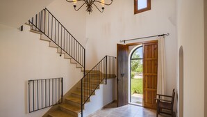 A staircase with a wooden finish, a black metal railing, and a chandelier.