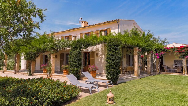 A villa with a covered patio, outdoor seating, and a well-maintained garden.