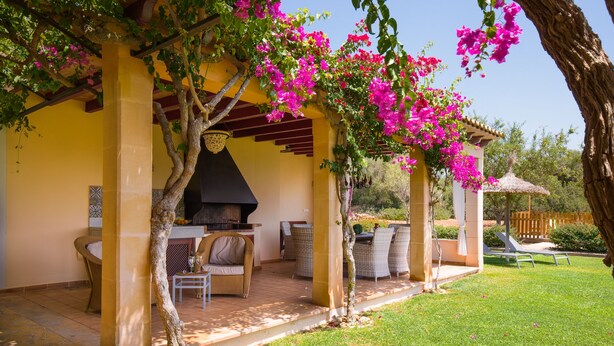 Un espace extérieur aménagé, abrité et doté de mobilier en osier, d’un barbecue intégré et de magnifiques bougainvilliers en fleurs.