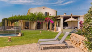 A house with a pool, outdoor seating, and a garden with pink flowers.