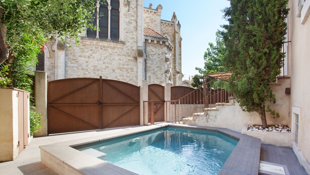 Una piscina con un muro de piedra y un portón de madera al fondo.