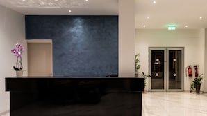 Uma receção com bancada escura, parede azul com textura e chão em mosaico.