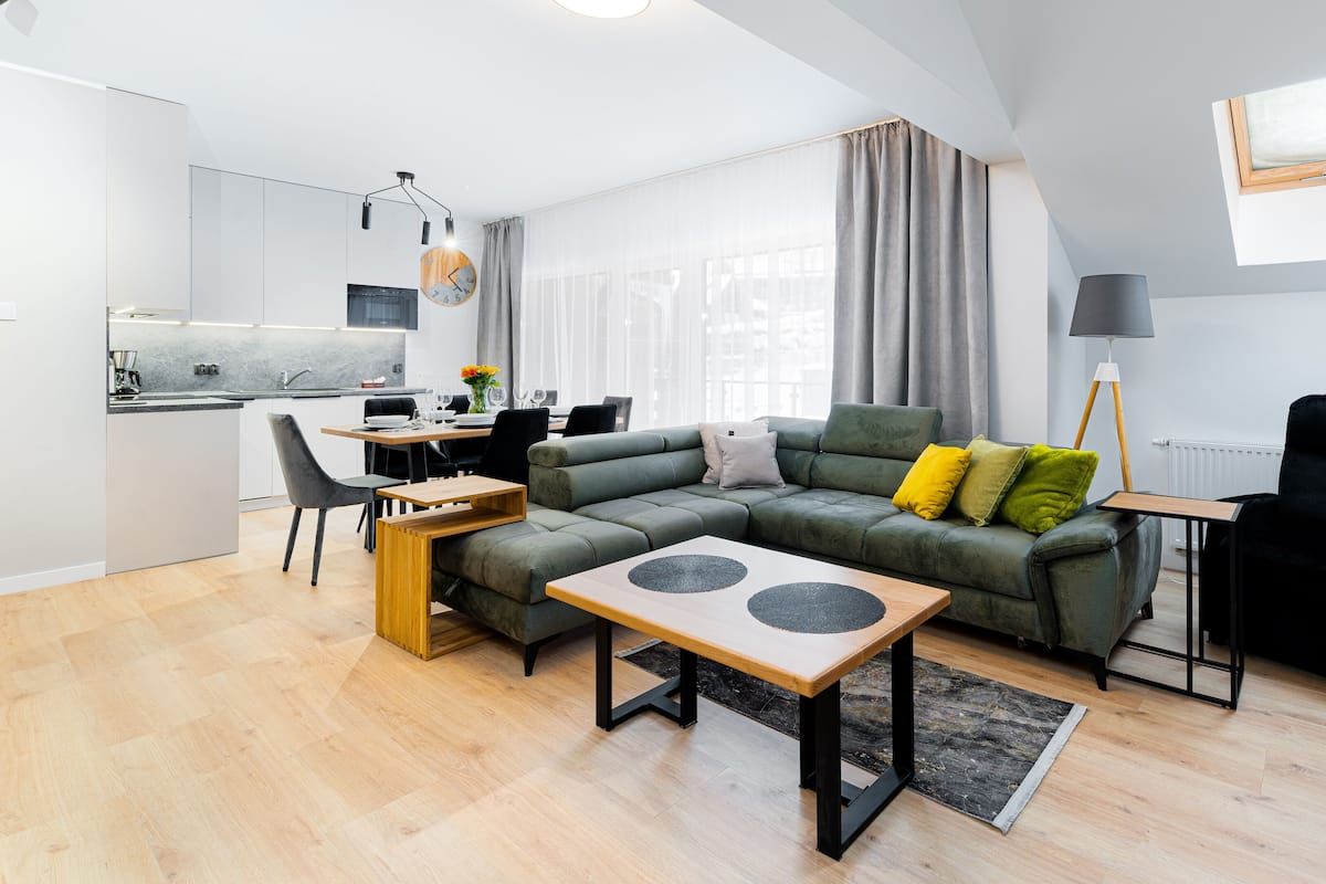 Un espacio habitable moderno con sofá, mesa de comedor y zona de cocina.