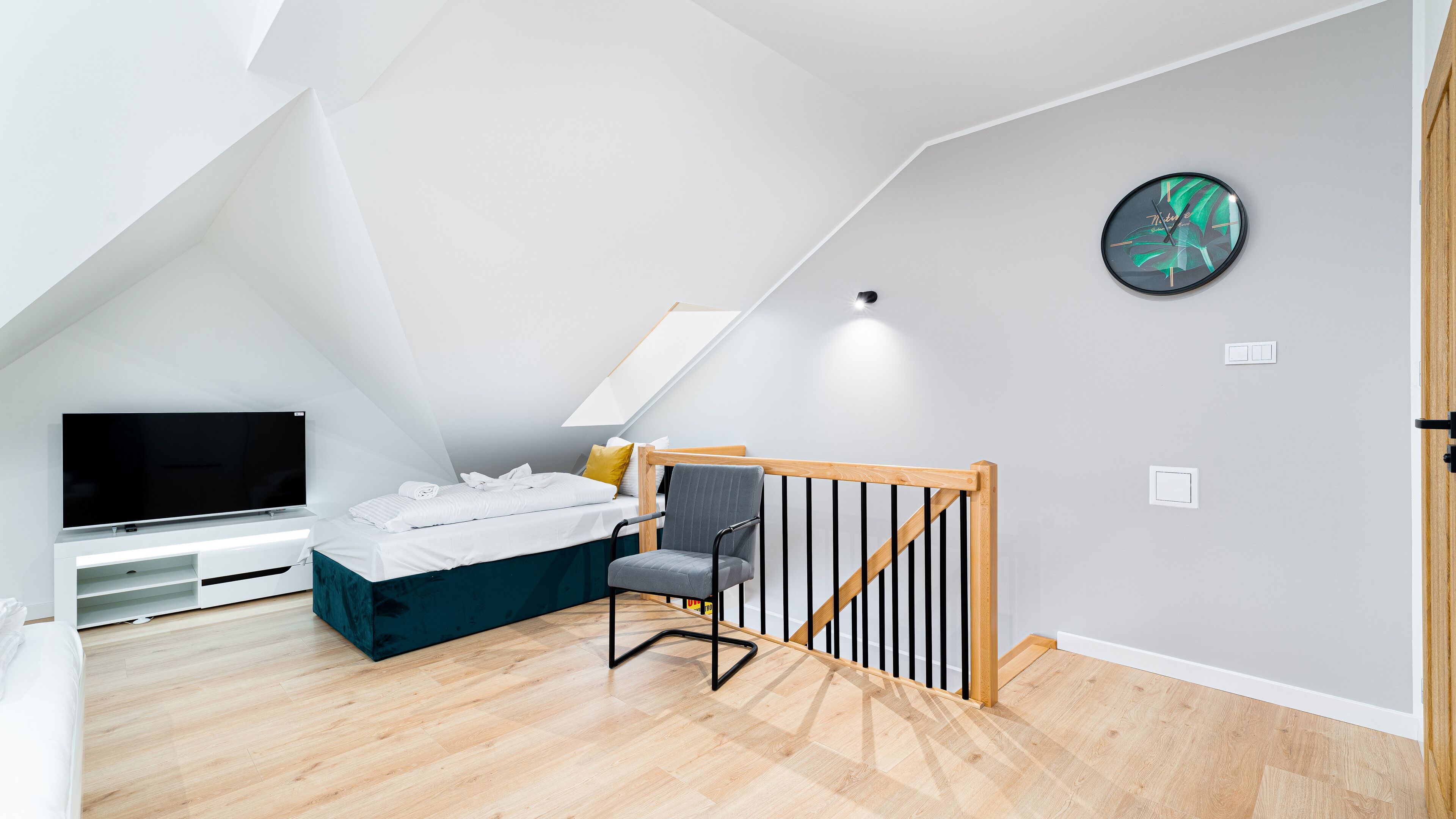 Una moderna camera da letto mansardata con un letto, una TV, una scrivania e una scala.