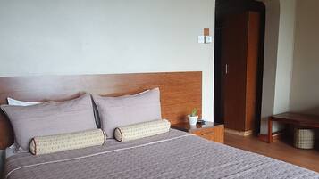 Cozy retreat with a large bed, wooden headboard, and potted plant.