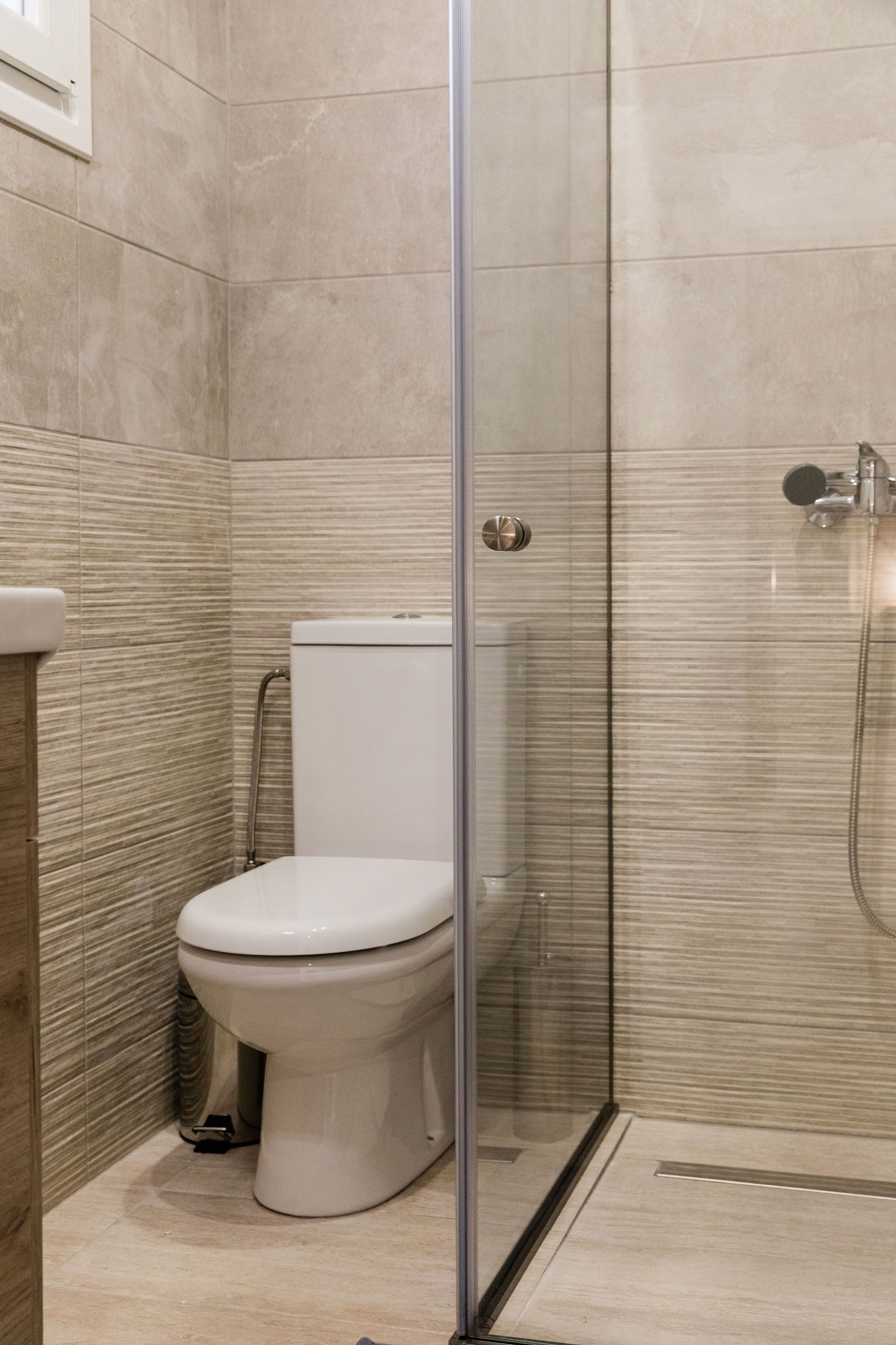 A modern bathroom with a glass-enclosed shower, a toilet, and a sink.