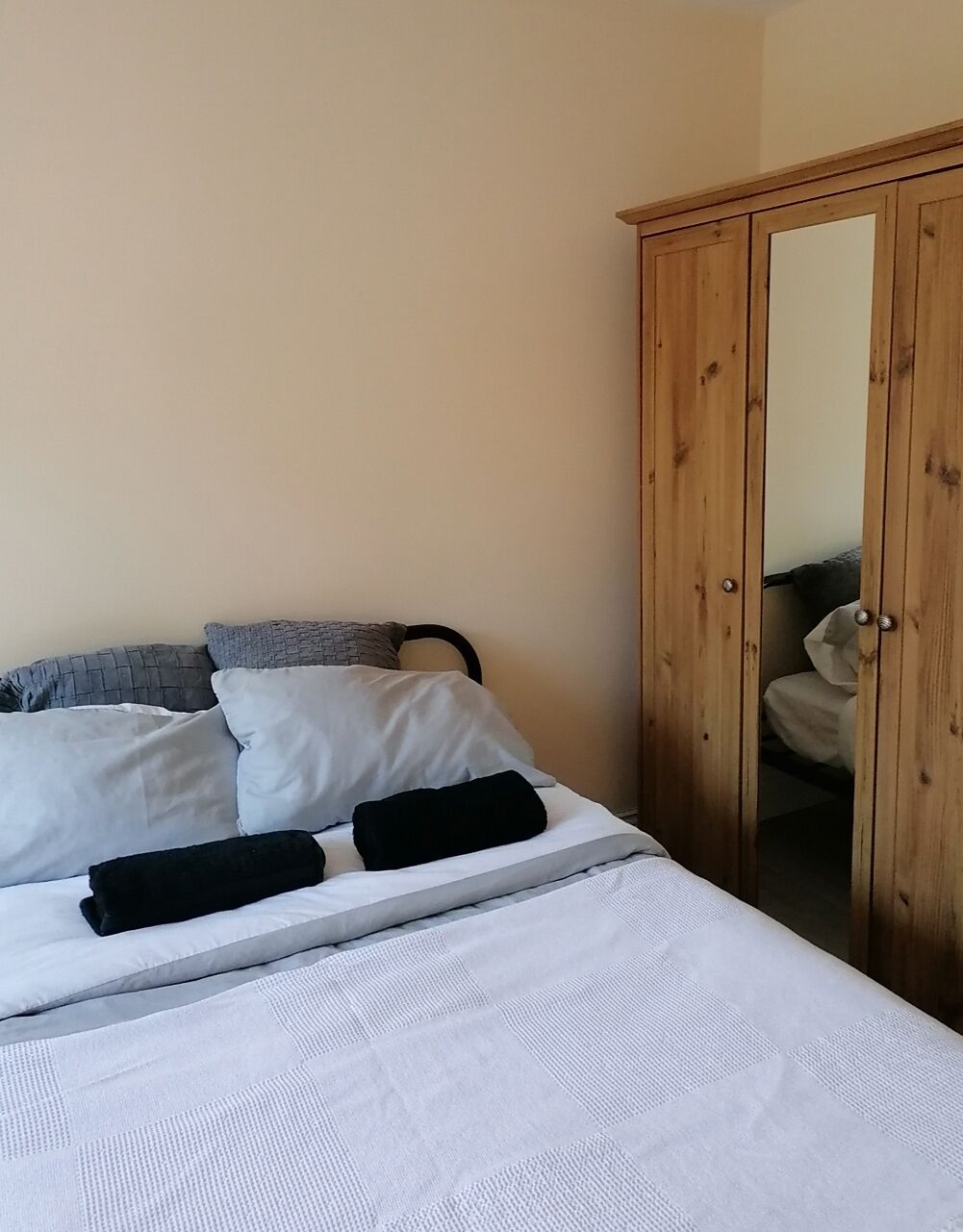 Une chambre à coucher avec un lit, des oreillers et une armoire en bois.