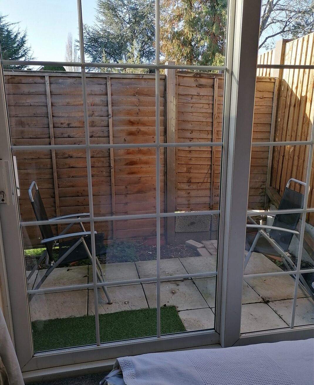 Un espace extérieur aménagé en patio, avec une clôture en bois, un portail en métal et une petite pelouse.
