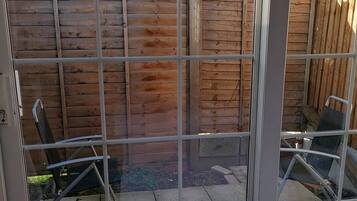 A patio area with a wooden fence, a metal gate, and a small patch of grass.