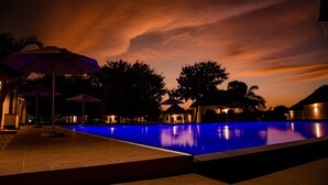 Una piscina con bordeado de azulejos, sombrillas y sillas de descanso.
