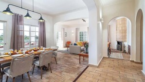 Un vaste espace de vie comprenant une table à manger dressée pour le petit-déjeuner, un canapé et une cheminée.