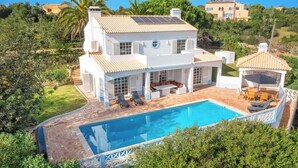 Une maison à deux étages avec une piscine, un espace salon extérieur et une terrasse couverte.