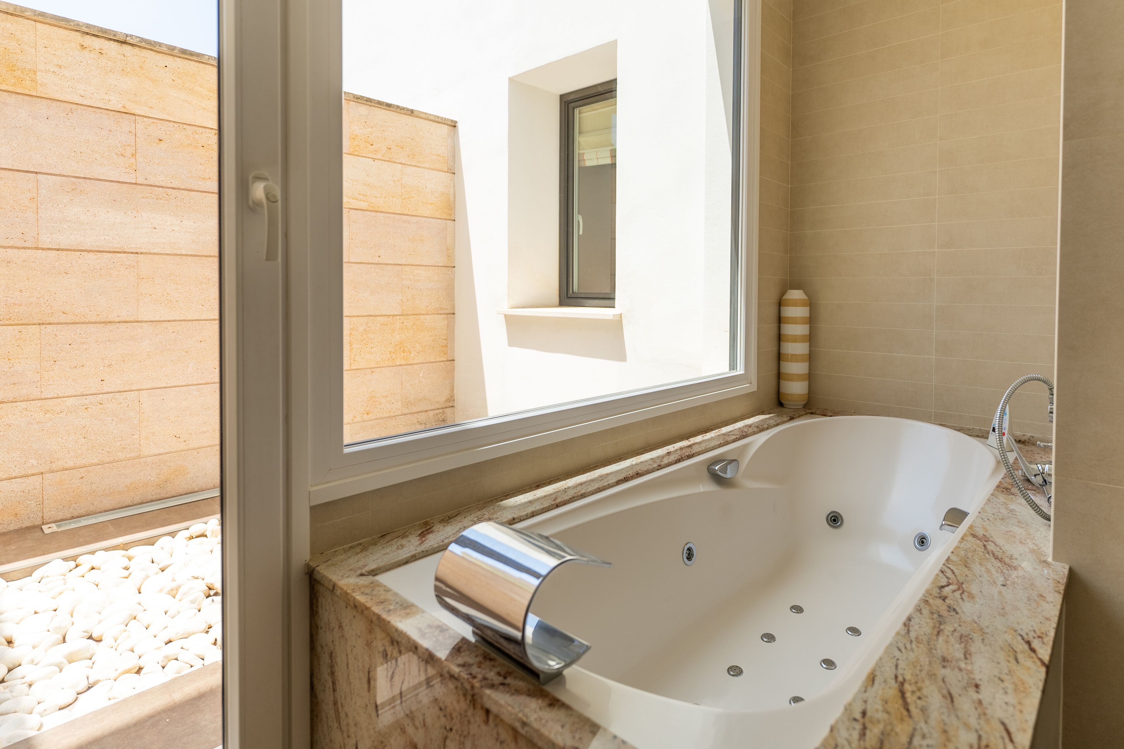Une salle de bain moderne avec une baignoire sur pieds, une fenêtre et un comptoir en marbre.