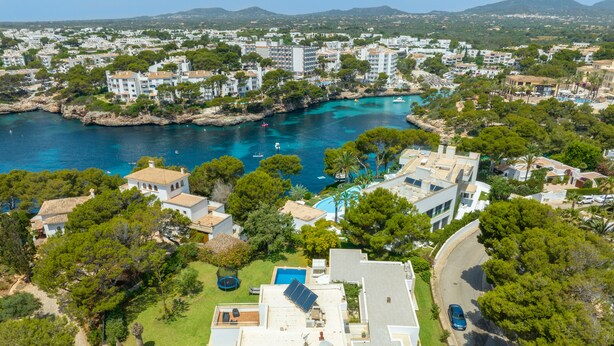 Un quartier résidentiel situé sur la côte, avec des maisons modernes, une piscine et une vue sur la mer.