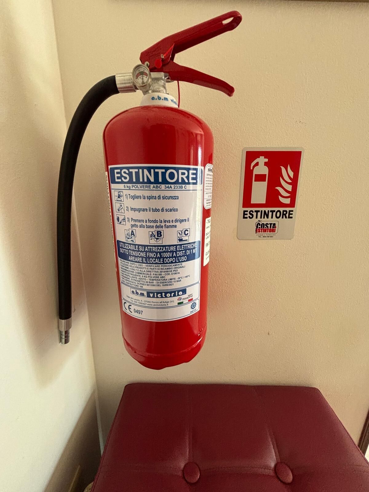 Extintor rojo montado en una pared, con un letrero de seguridad contra incendios cerca.