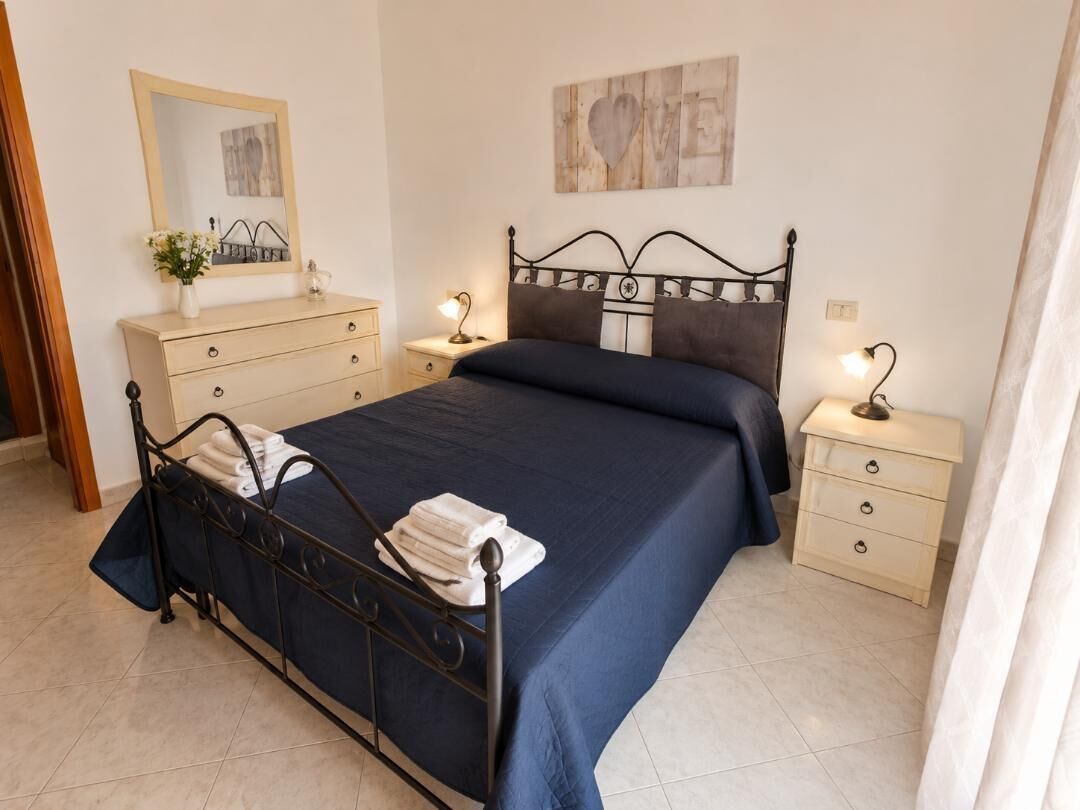 Ein Schlafzimmer mit einem Bett, Nachttischen, einer Kommode und einem Spiegel.