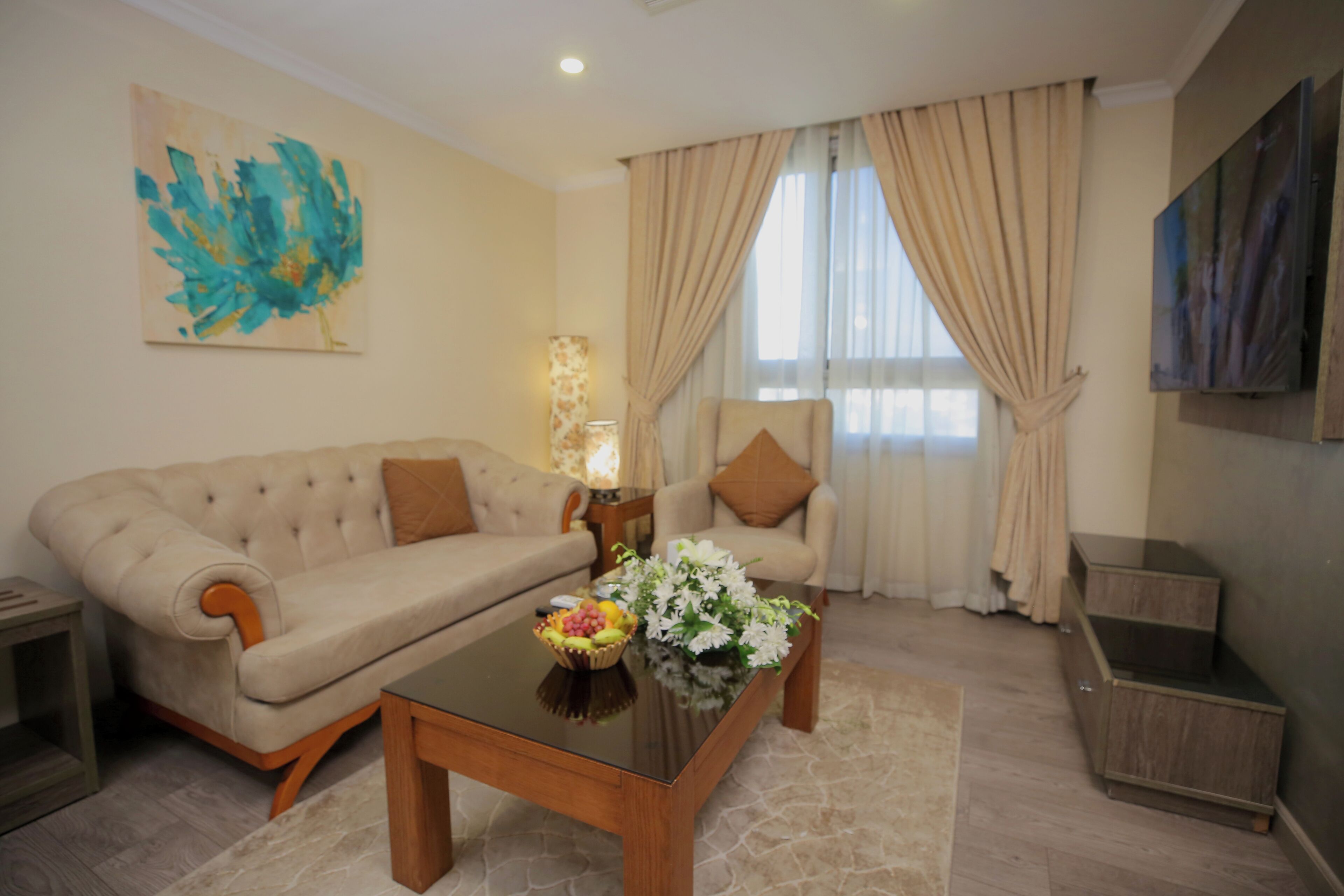 Una sala de estar con sofá, sillón, mesa de centro y un cuadro en la pared.