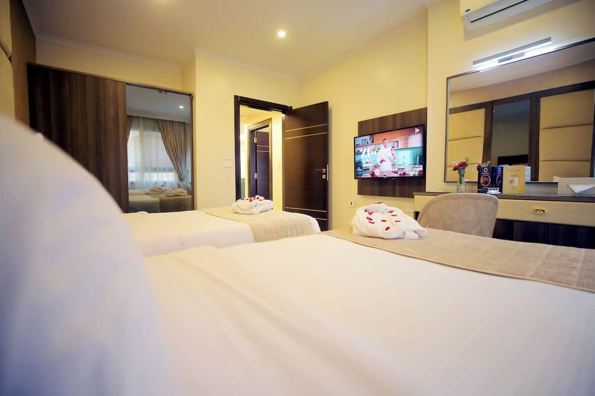 A hotel room with two beds, a TV, a desk, and a mirror.