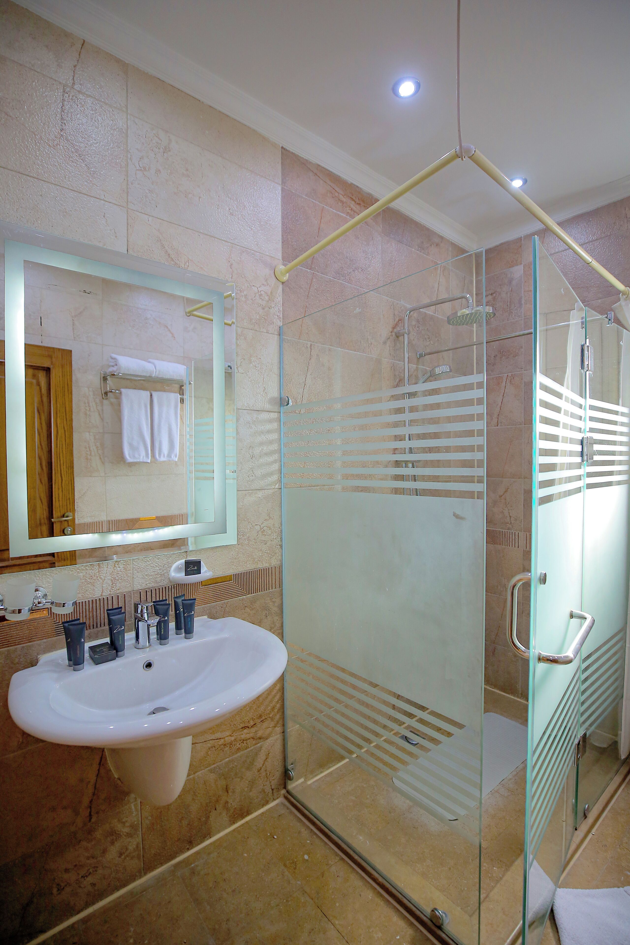 Une salle de bain dotée d’une douche à parois de verre, d’un lavabo avec plusieurs robinets et d’un miroir au-dessus du lavabo.