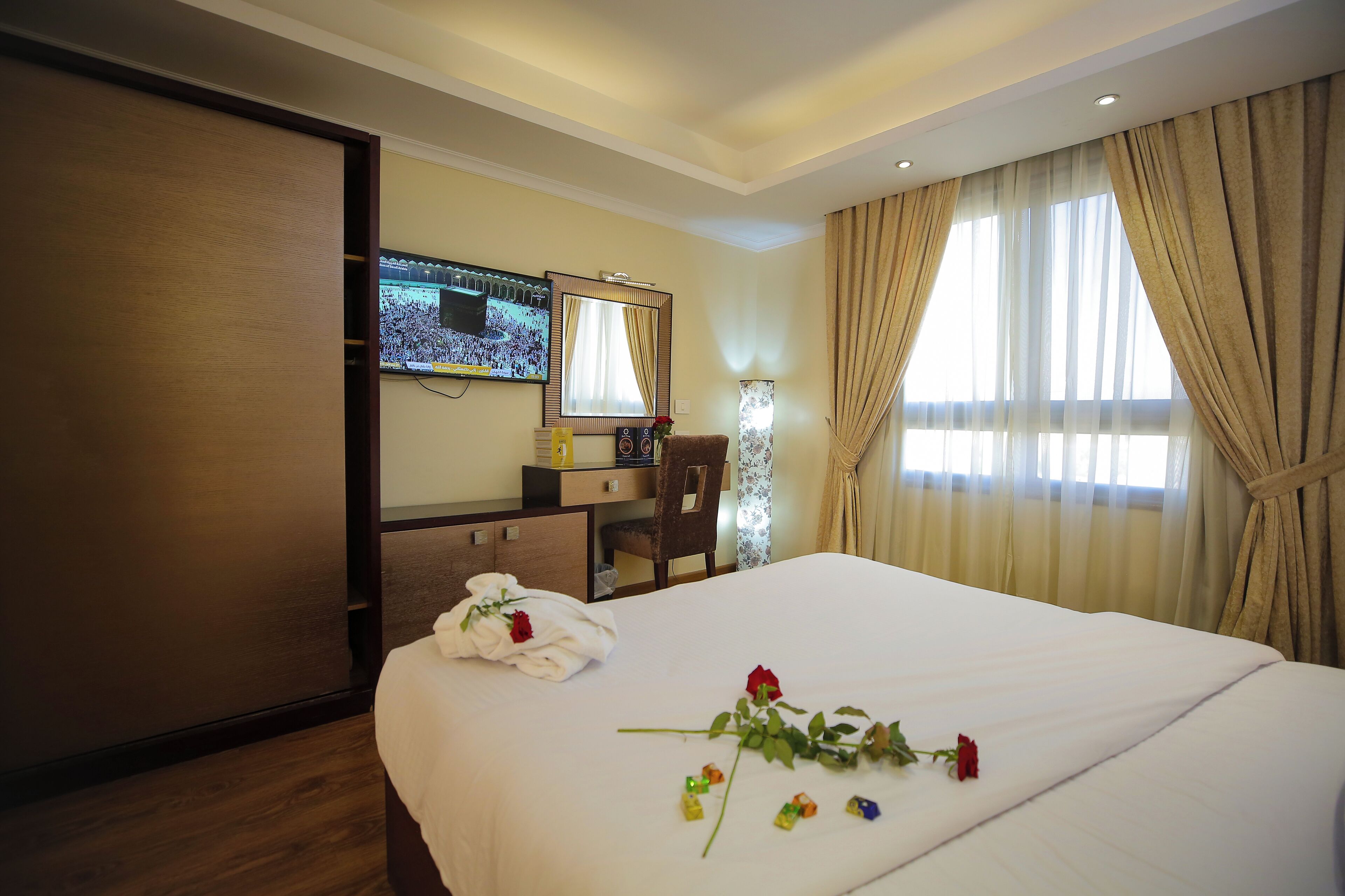Ein Hotelzimmer mit Bett, Schreibtisch, Fernseher und Vorhängen.