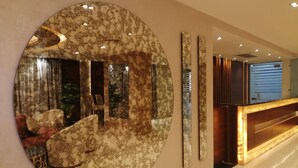 A modern lobby with a large circular mirror, a reception desk, and a seating area with a plant. - Cairo Taj Hotels & Suites - Dokki (Giza)