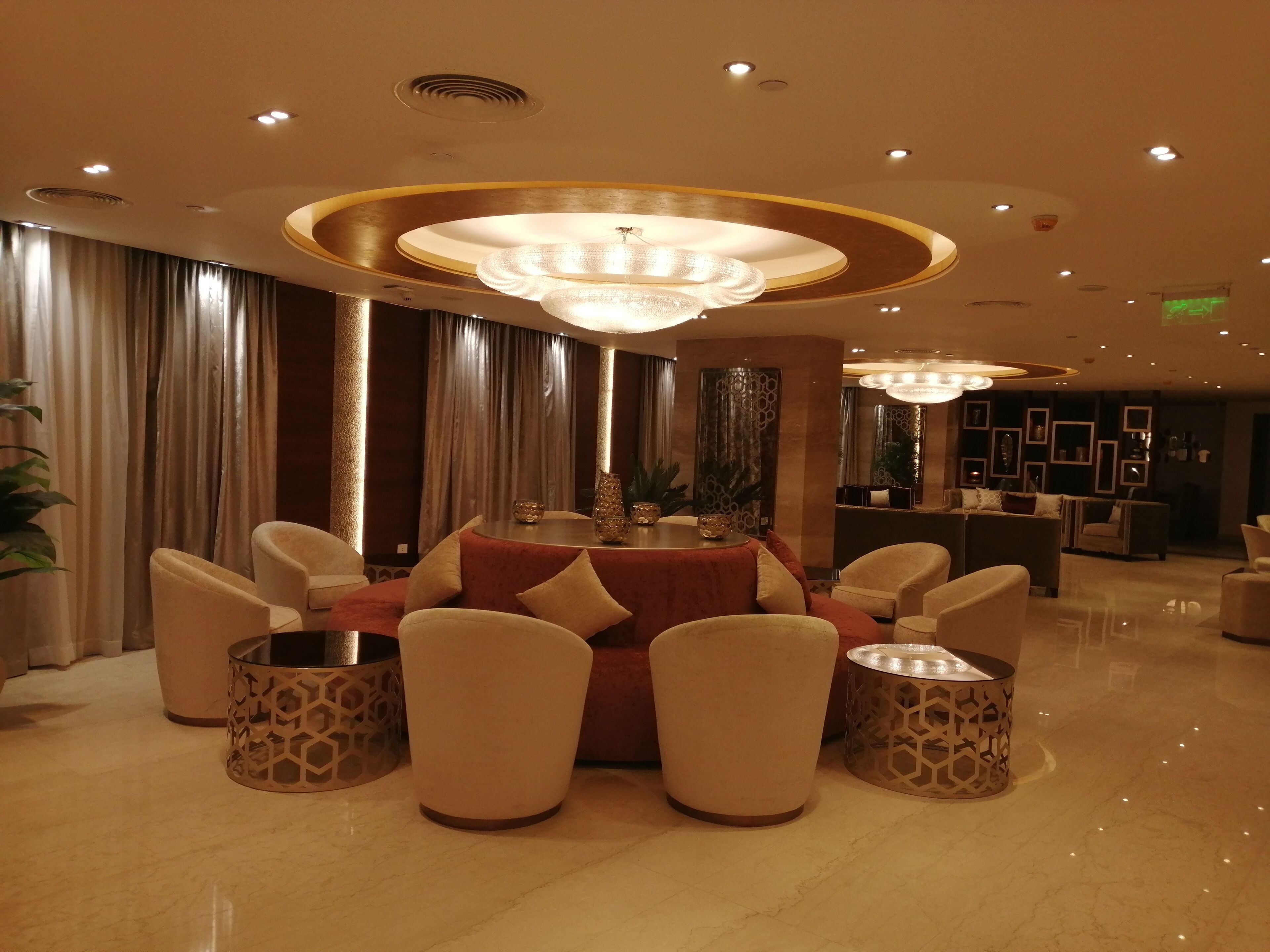 Un hall d’entrée moderne avec une table ronde, des sièges confortables et un éclairage décoratif.