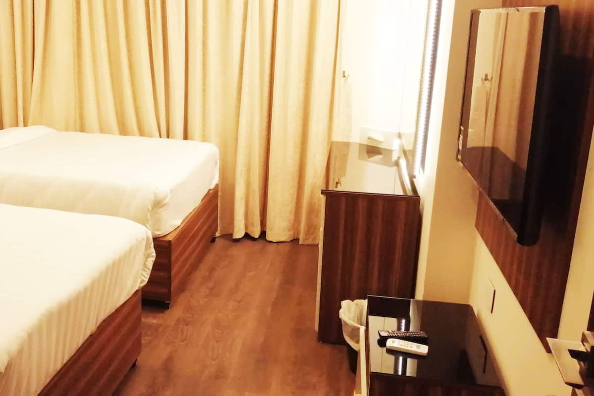 A hotel room with two beds, a TV, a desk, and a mirror.