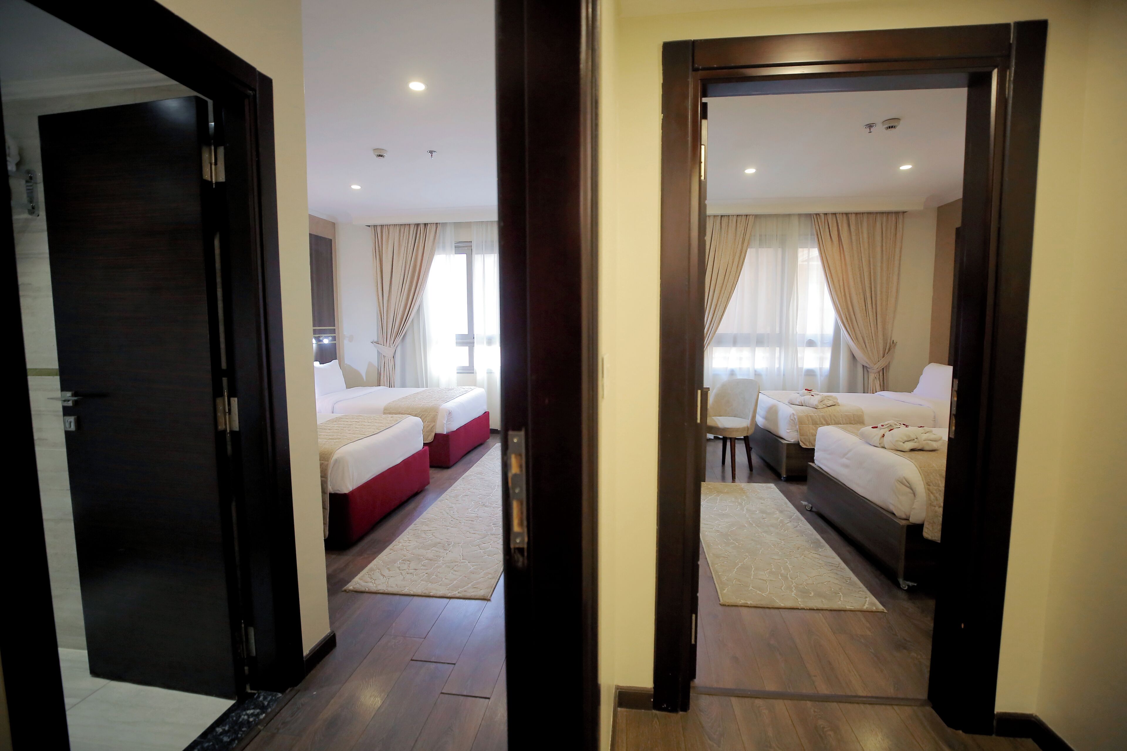 A hotel room with two beds, a small table, and a view of the city.