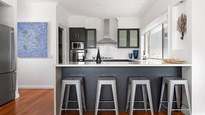 Une cuisine moderne dotée d’un îlot central, de tabourets de bar et d’un élément décoratif mural.