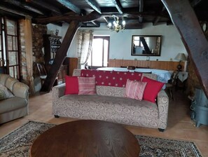 A cozy living room with a patterned sofa, a round wooden coffee table, and a stone wall.