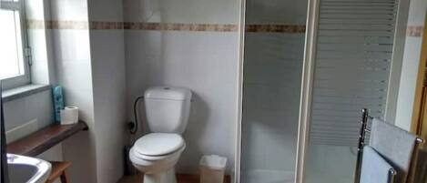 Une salle de bain comprenant des toilettes, un espace douche et un lavabo.