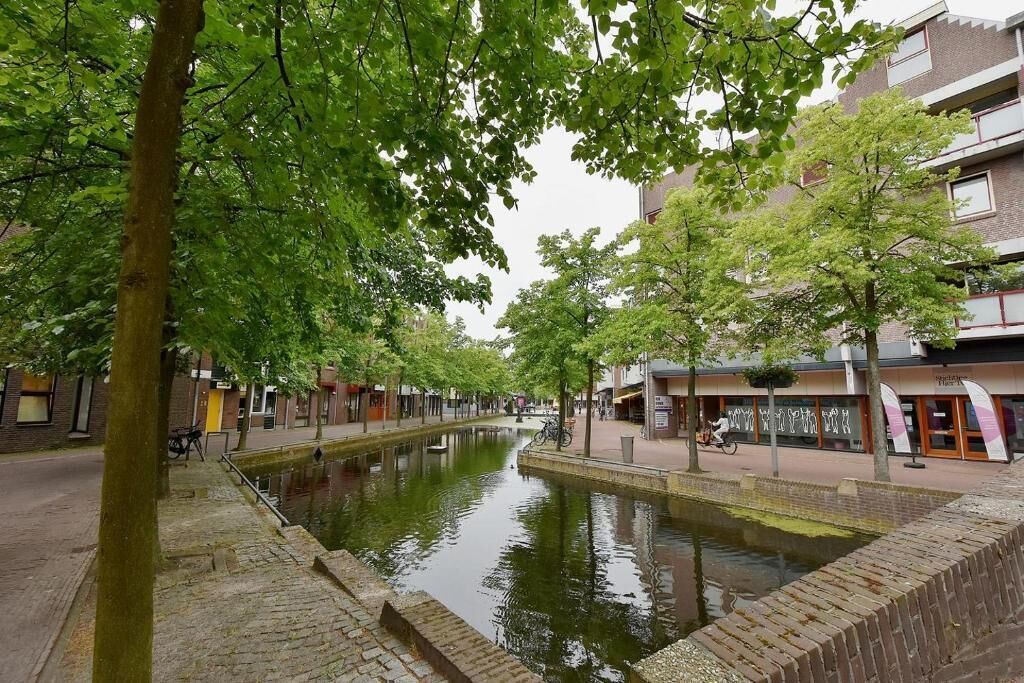 A canal lined with trees and buildings, with a bike parked by the water.