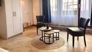 A room with a large wardrobe, two chairs, a small table with a plant, and a view through a window with curtains. - Bed and Ontbijt Haddock (Almere)