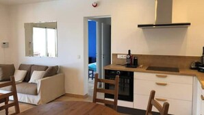 A compact living space with a kitchenette, a dining area with a wooden table and chairs, a sofa, and a window. - Villa with superb sea view, swimming pool, 350 metres from the beach, air conditioning, garden (LE LAVANDOU)