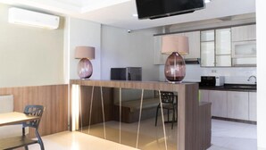 A modern hotel room with a dining area, a flat-screen TV, and a kitchenette. - OYO 3811 Best Inn Hotel (Jakarta)
