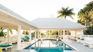 A covered swimming pool with lounge chairs and a pergola.