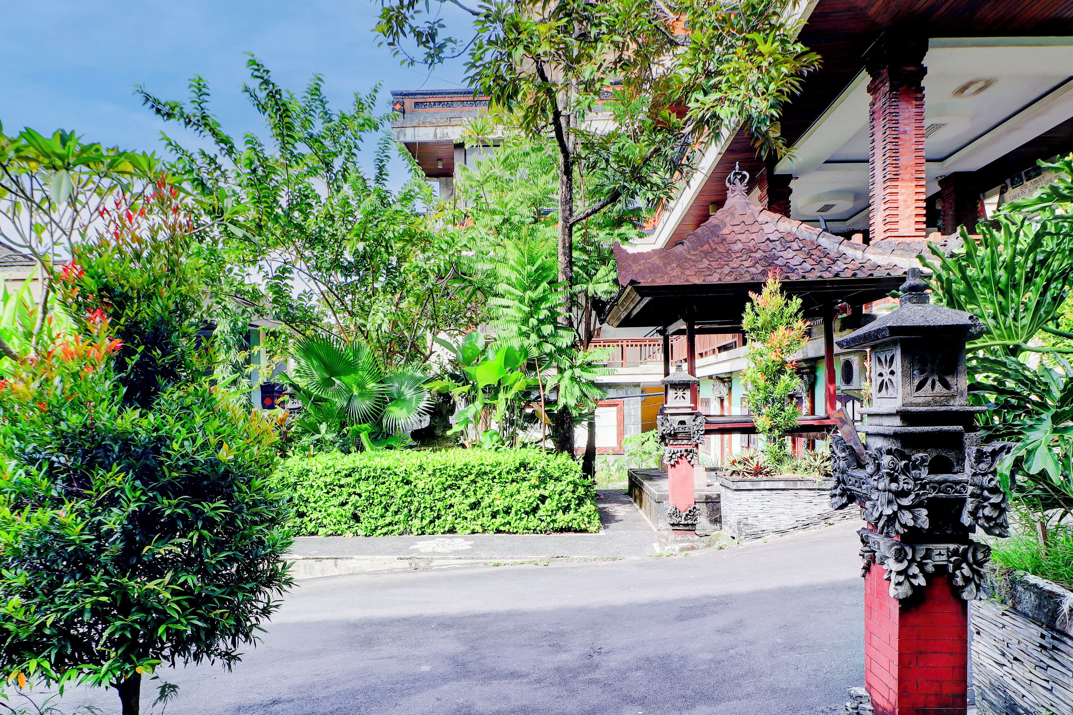 A traditional building with a tiled roof, surrounded by lush greenery and a paved pathway.