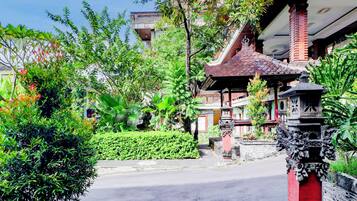 A traditional building with a tiled roof, surrounded by lush greenery and a paved pathway.