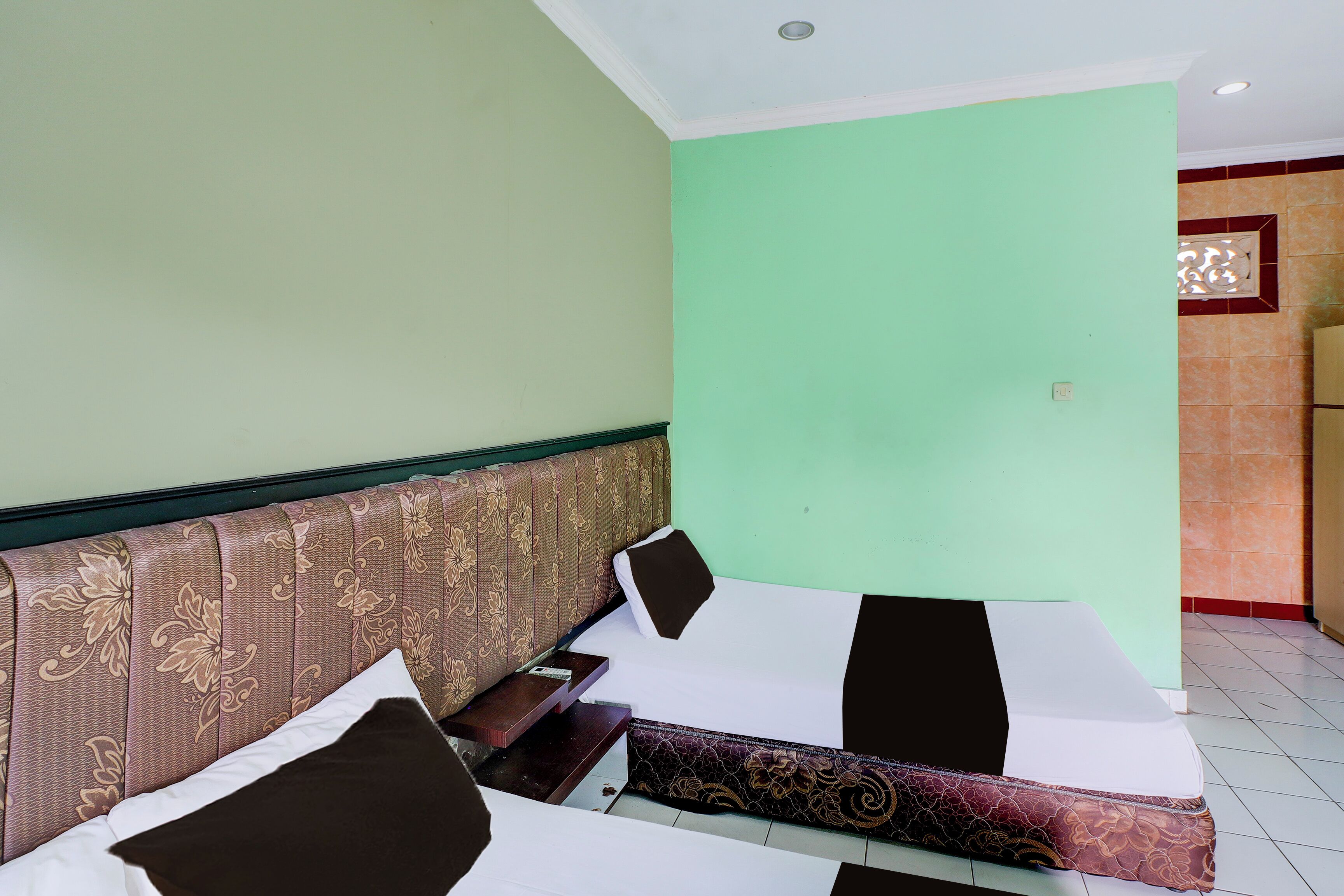 Una habitación de hotel con una cama, una mesita de noche y un panel decorativo en la pared.