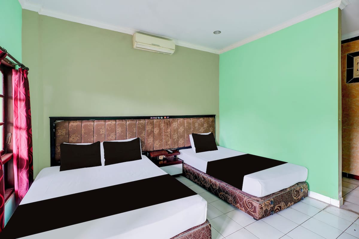 A hotel room with two beds, a headboard, a nightstand, and a window with curtains.