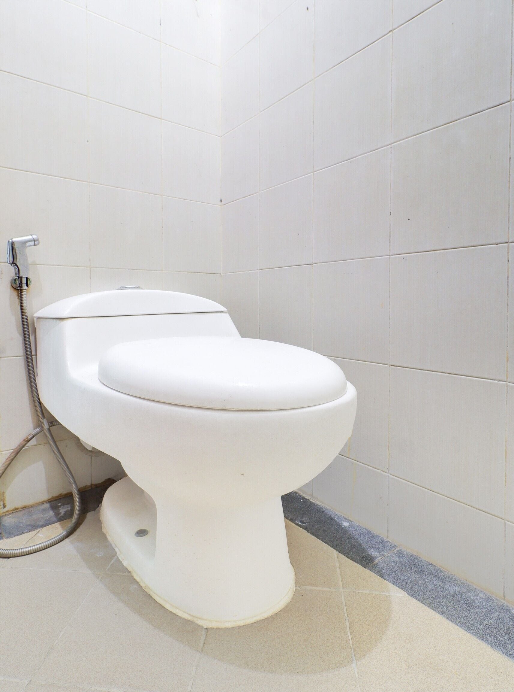 A white toilet in a bathroom with white tiles on the walls and floor.